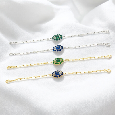 Set of gold and silver bracelets with gemstone accents on a white fabric background