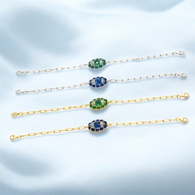 Set of gold bracelets with gemstone accents on a light blue background