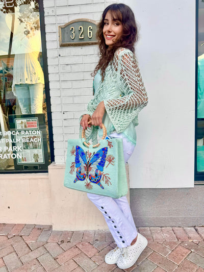 Woman holding a handbag with butterfly design in front of a store
