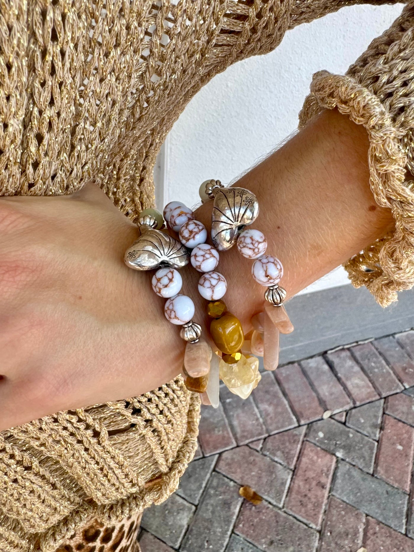 Close-up of a hand wearing multiple bracelets on a textured surface