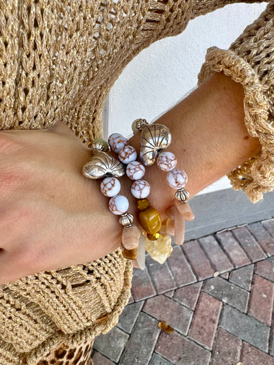 Close-up of a hand wearing multiple bracelets on a textured surface