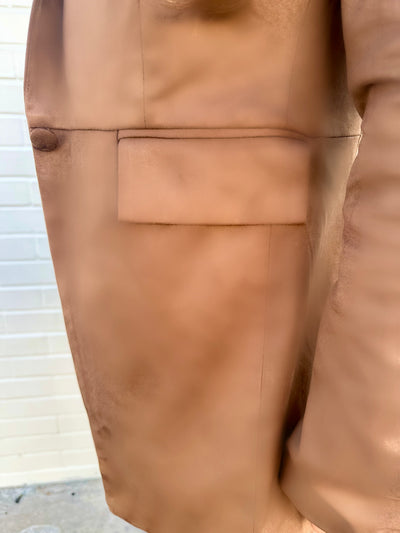 Close-up of a beige suede-feel jacket with a pocket detail.
