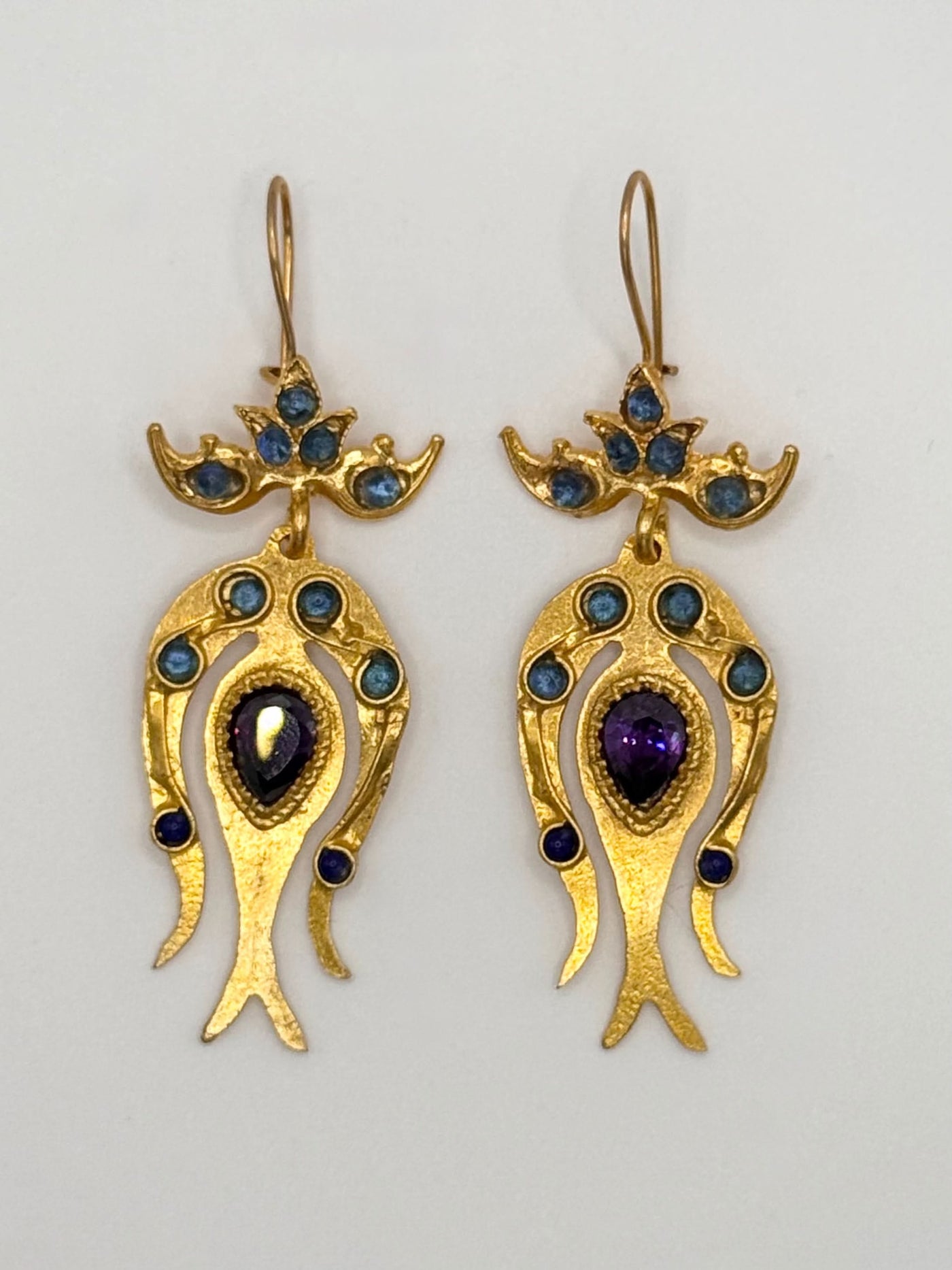 Pair of gold earrings with gemstones on a light gray background