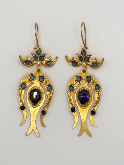 Pair of gold earrings with gemstones on a light gray background