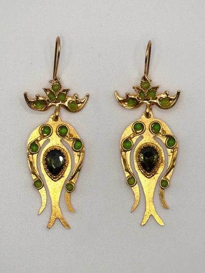 Gold earrings with green gemstones on a gray background