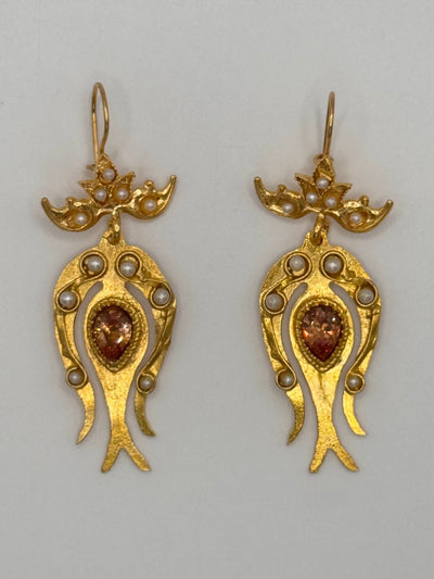 Pair of gold earrings with gemstones and pearls on a gray background