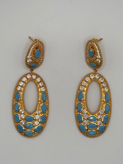 Gold earrings with blue stones and clear gemstones on a gray background