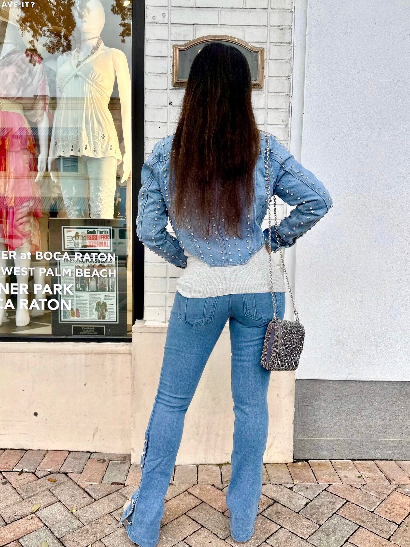 Woman in blue denim outfit standing in front of a store window display.