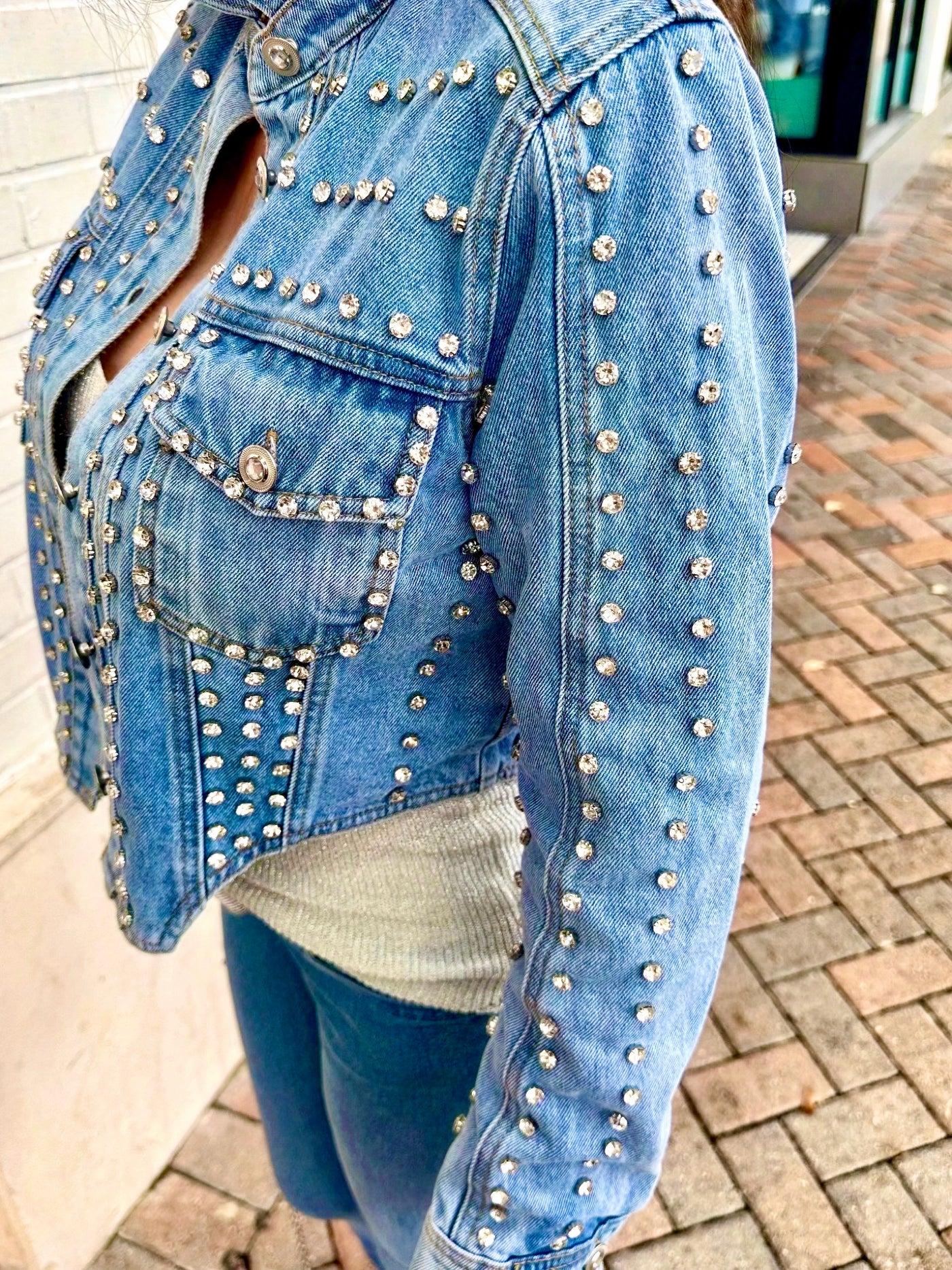 Denim jacket with rhinestone embellishments on a paved surface