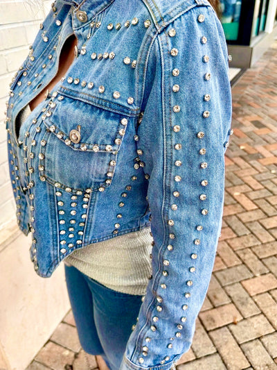 Denim jacket with rhinestone embellishments on a paved surface