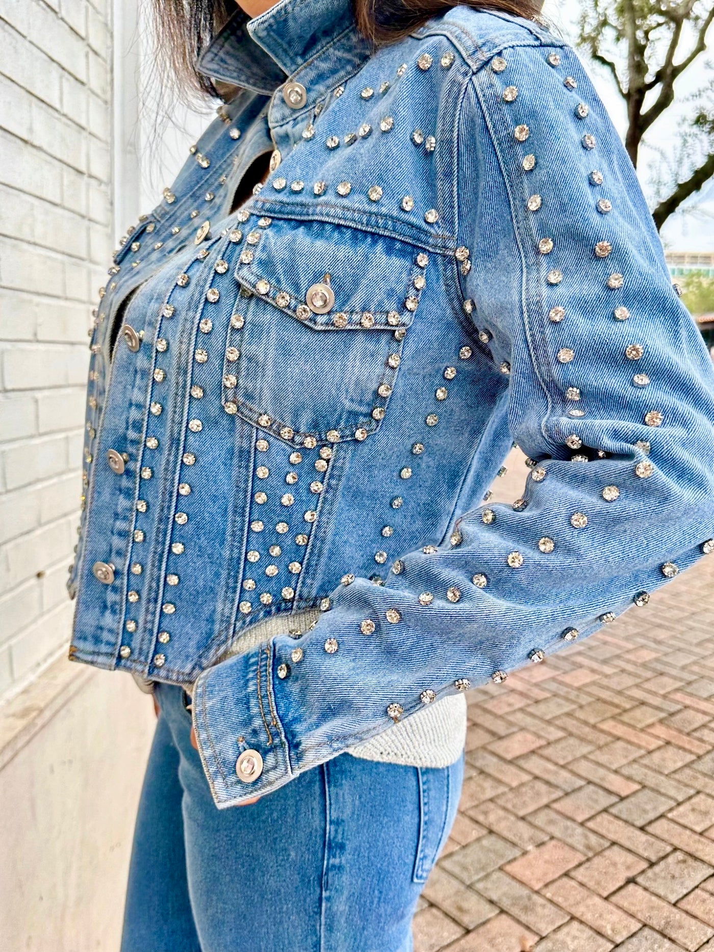 Denim jacket with silver studs worn by a person outdoors.